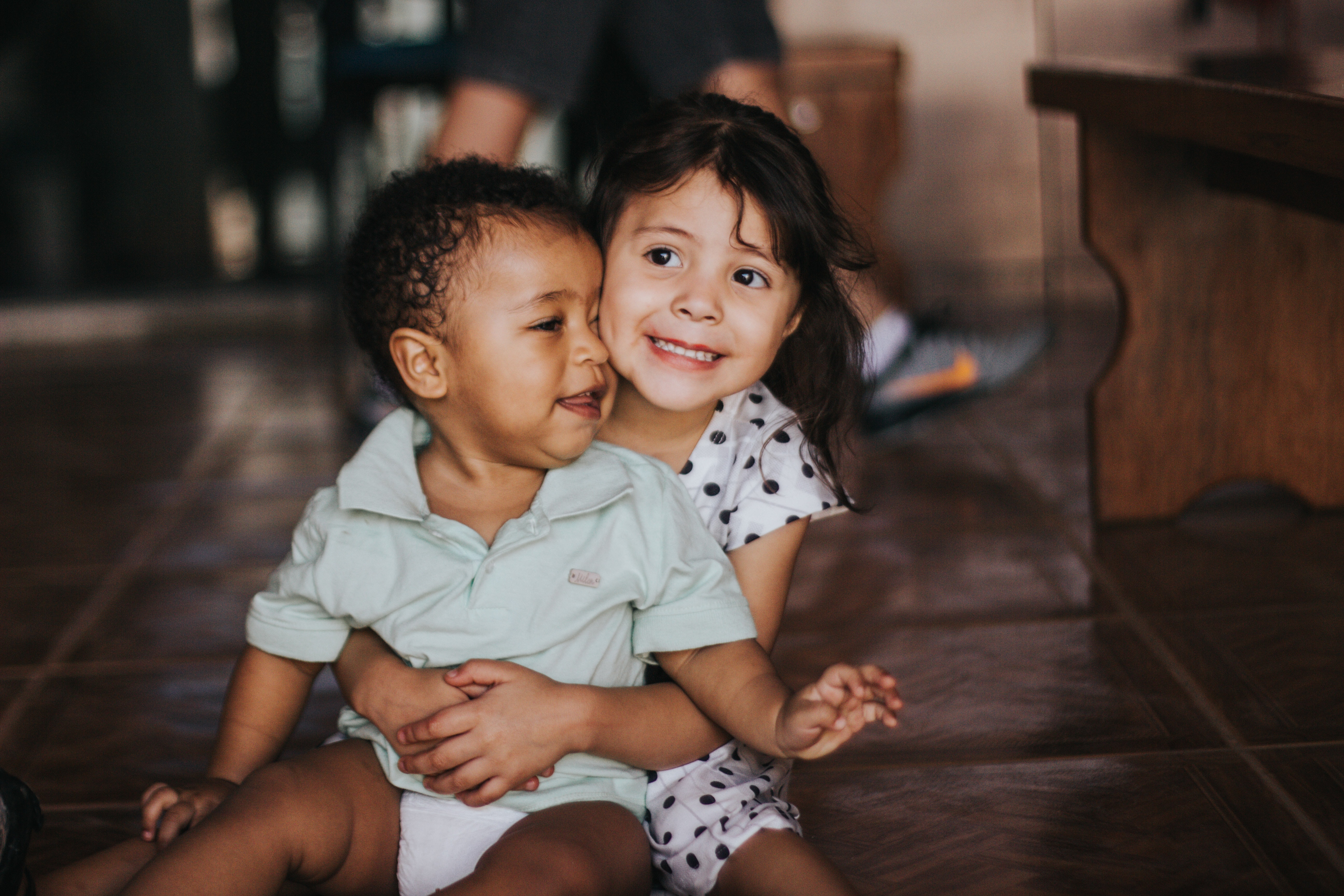A girl holding her little brother in her lap.