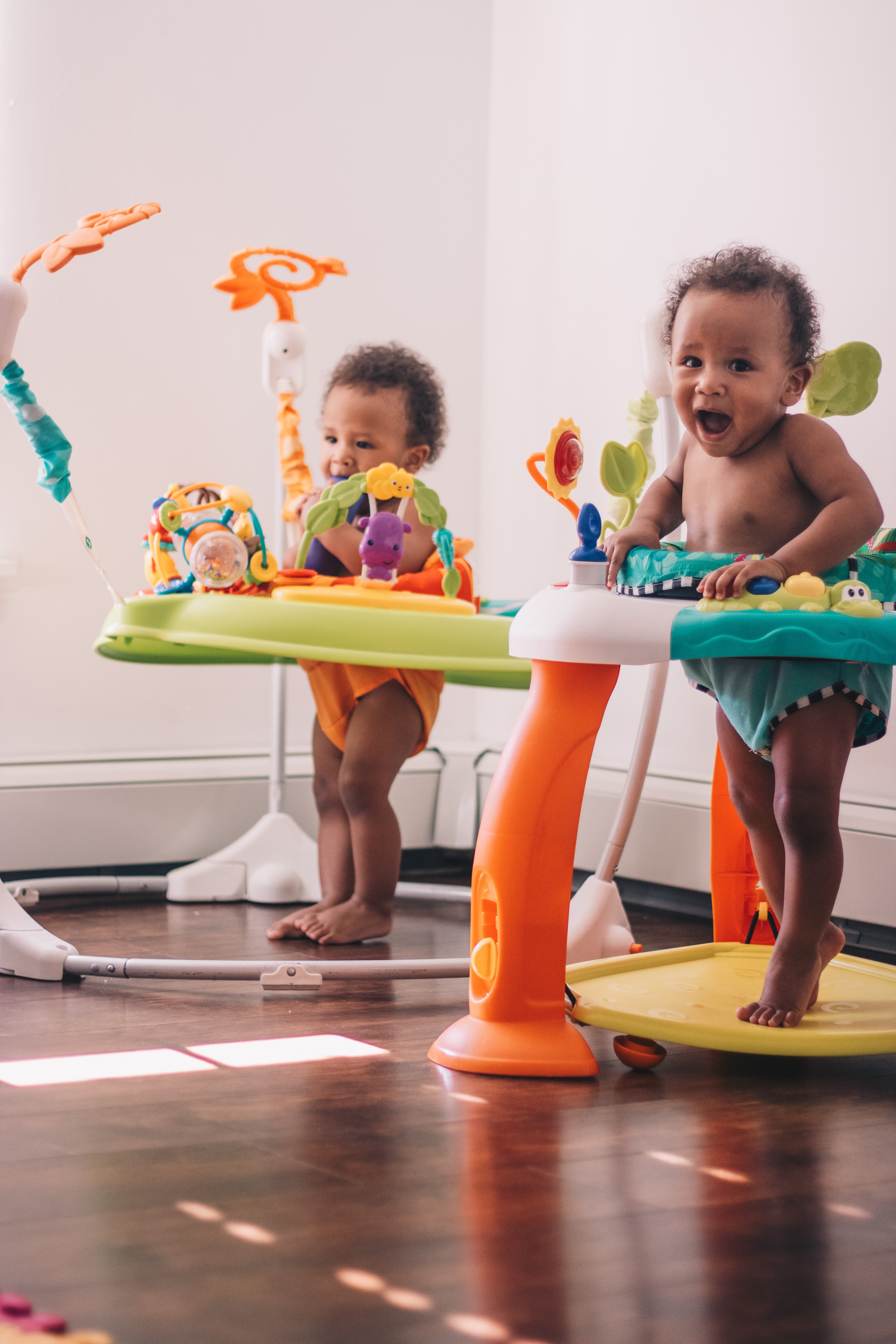 Two young children playing in their standing chairs.